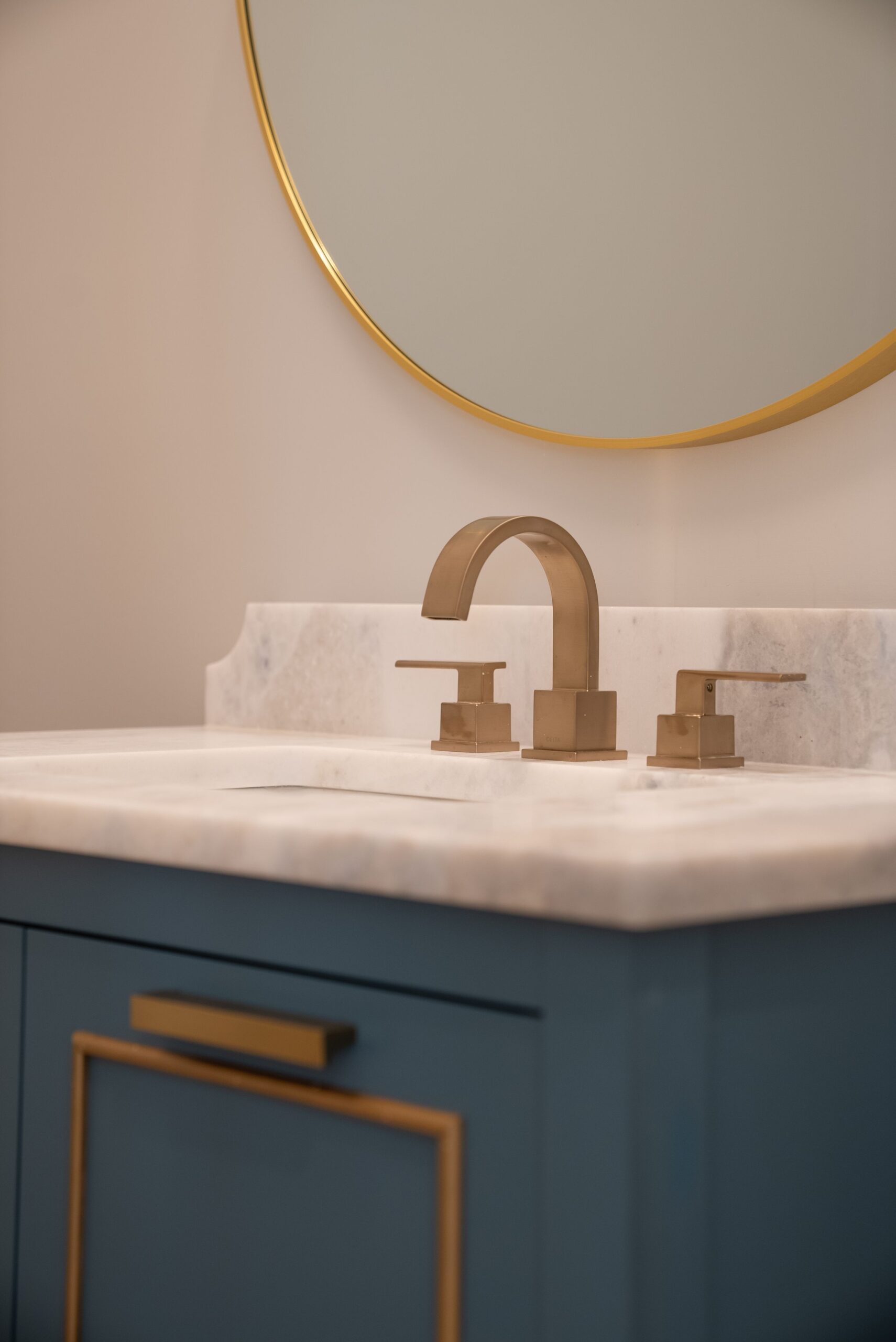 A bathroom sink with gold faucet and marble counter.
