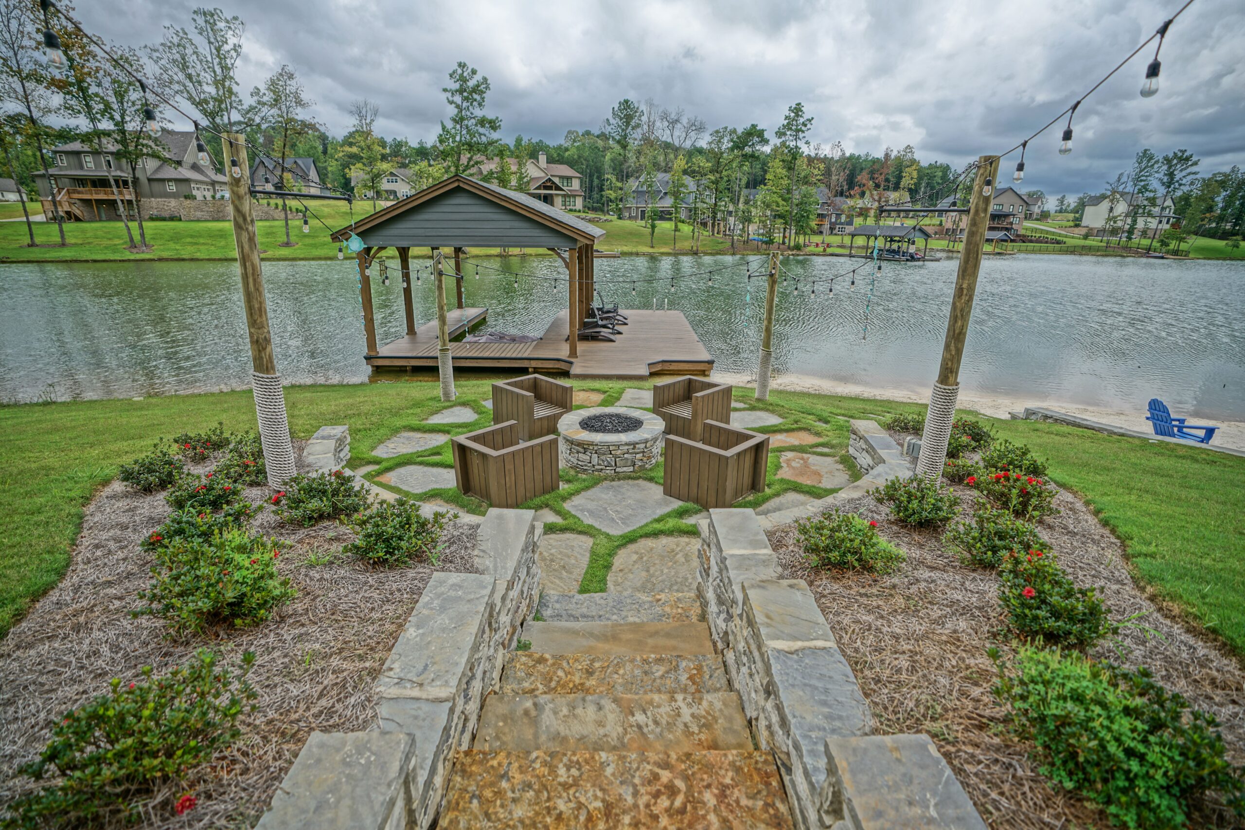 A patio area with fire pit and gazebo by the water.