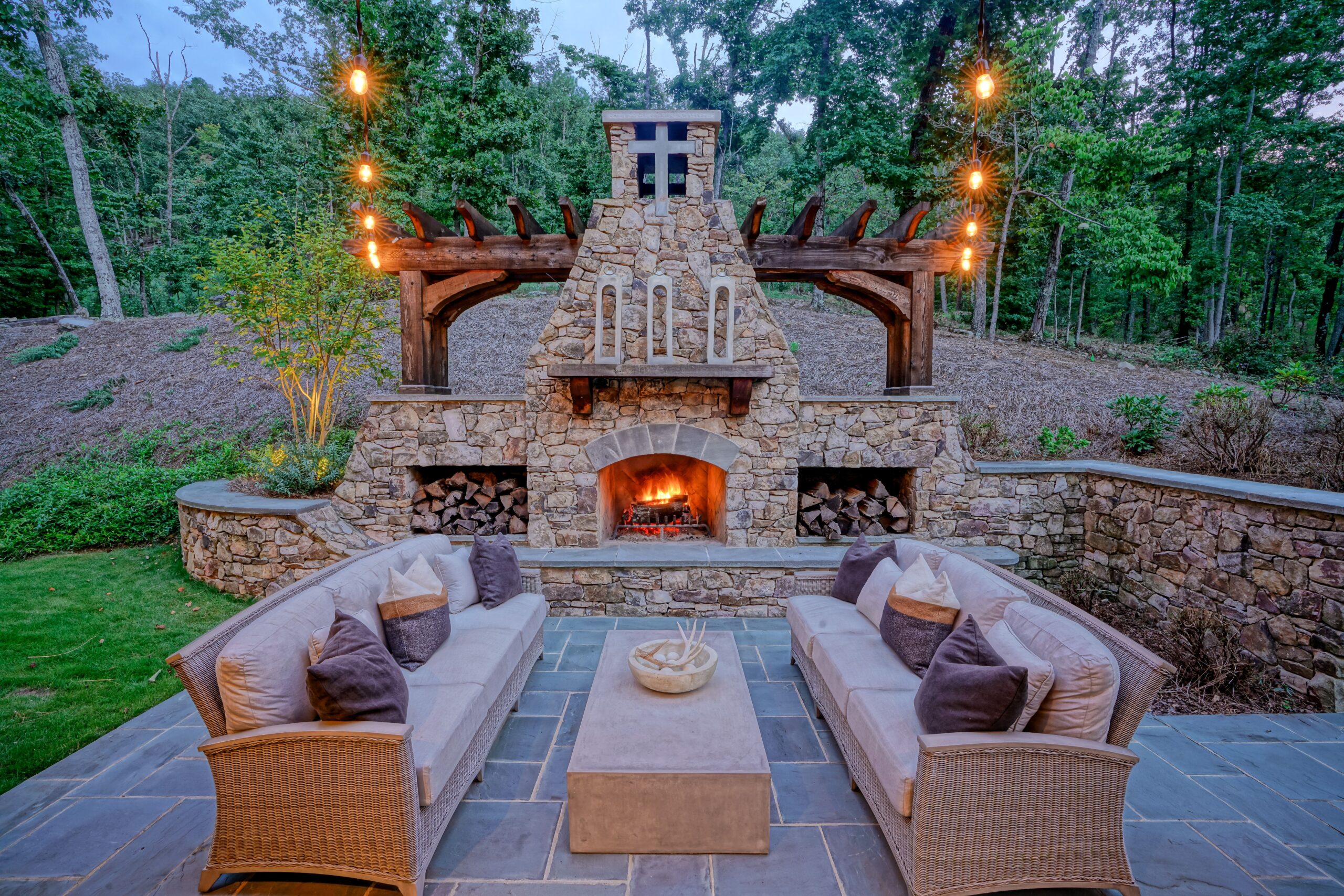 A stone patio with a fireplace and outdoor furniture.